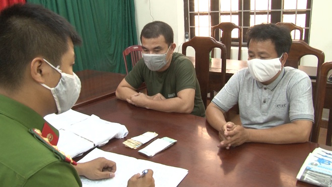 Nguyễn Văn Quảng (áo nâu) cùng một nghi can khác làm việc với cơ quan điều tra